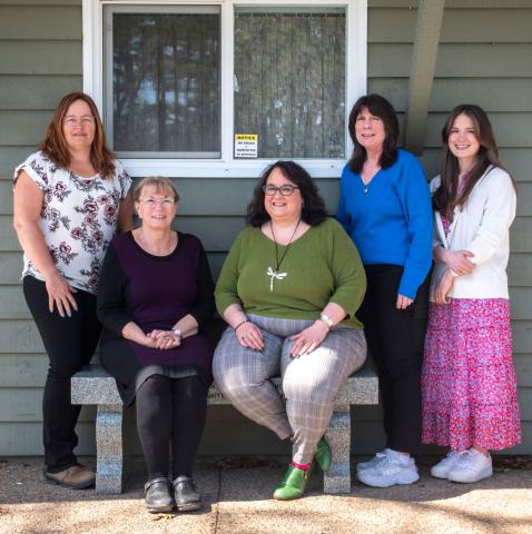 Five women standing in front of a window