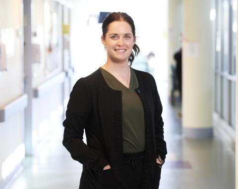 Lady standing smiling facing the camera in a hospital hallway