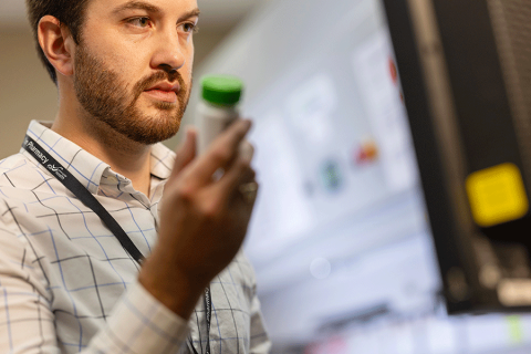 Pharmacist looking at a screen holding a pill bottle