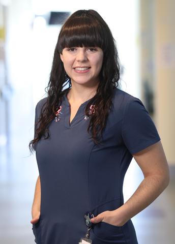 woman standing in a bright background wearing a blue smock
